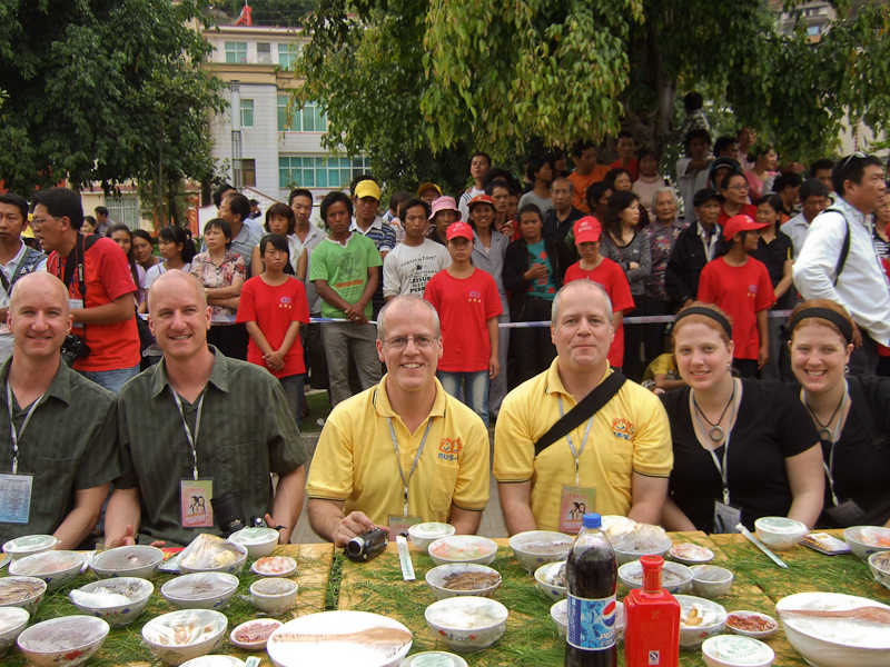 May 02, 2010@18:24<br/>Here we are, ready to dig in.  Local officials sat across from all of us, and red-shirted volunteers on both sides of the street held hands to form a barrier to keep the crowds back.  Seriously - crowding in to watch us eat!