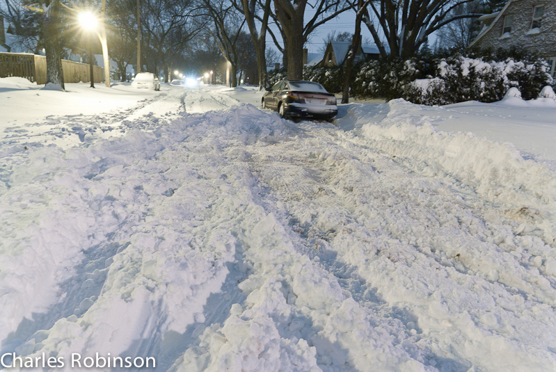 December 11, 2010@18:25<br/>This whole street was unplowed, but the car on the right there cleared it all out so he/she could get off of a route that is being plowed next.